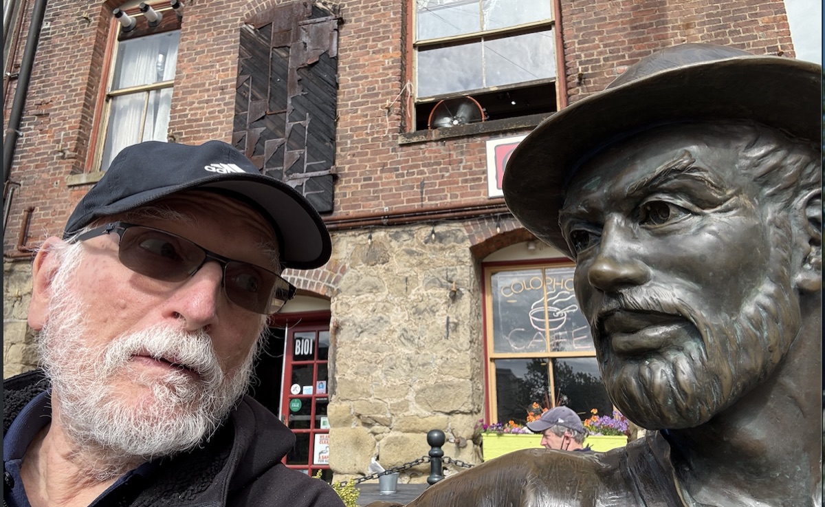 Howard Jachter beside a bronze prospector statue outside a cafe.